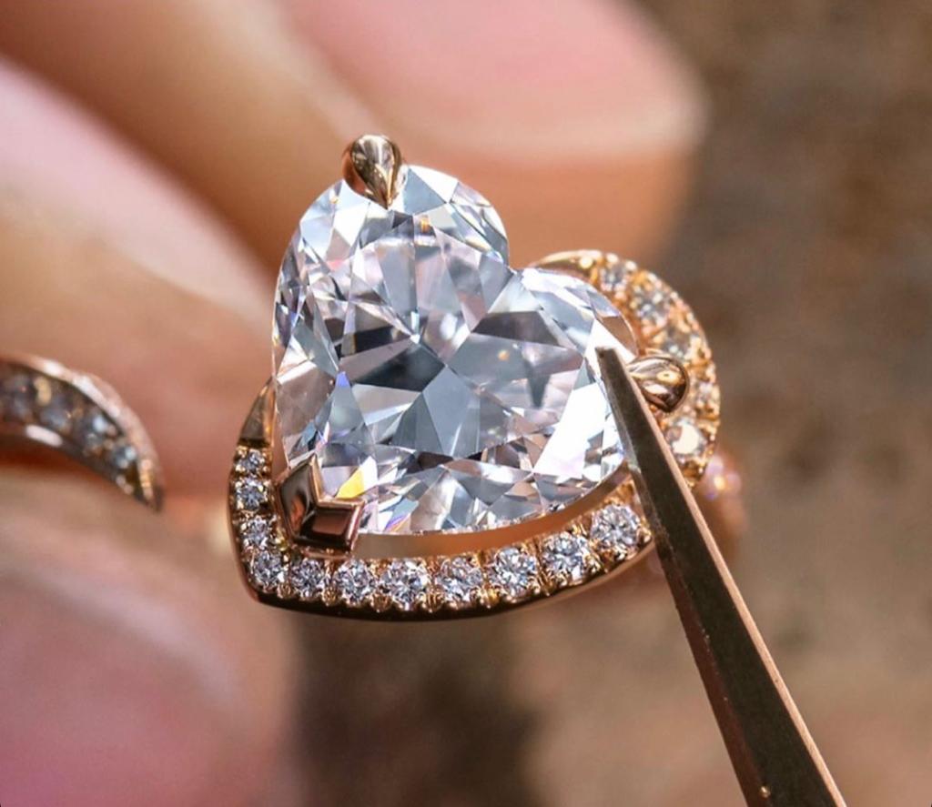 Heart-shaped diamond halo ring held with tweezers