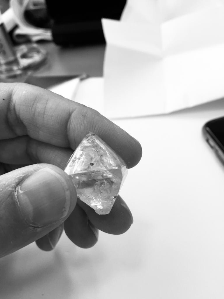 Rough diamond crystal held between fingers